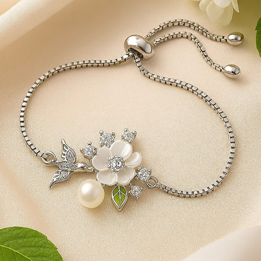 Silver bracelet with floral design and pearl on beige surface with flowers and leaves