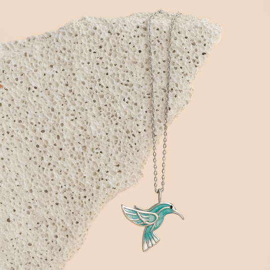 Necklace with a turquoise hummingbird pendant on a textured beige surface