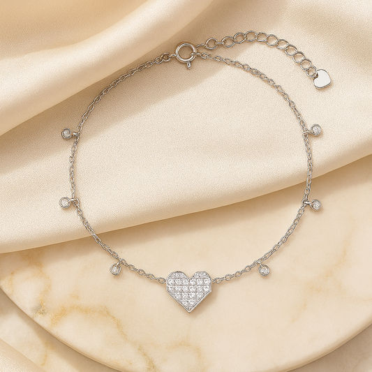 Silver bracelet with a heart-shaped charm on a beige fabric background