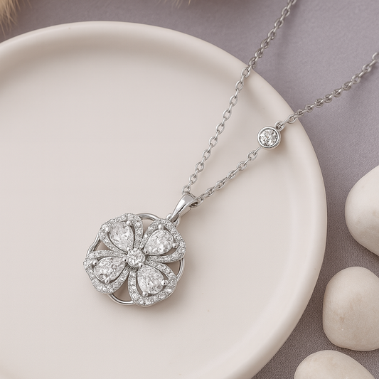 Silver necklace with a floral pendant on a beige plate with stones in the background