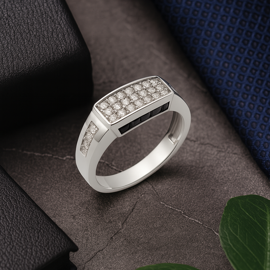 Silver ring with embedded stones on a textured surface with a plant leaf.
